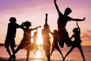 Silhoutte Of Group Of Boys And Girls Dancing In A Beach Background.